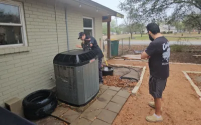 Two men working on a home heating and air conditioning unit.